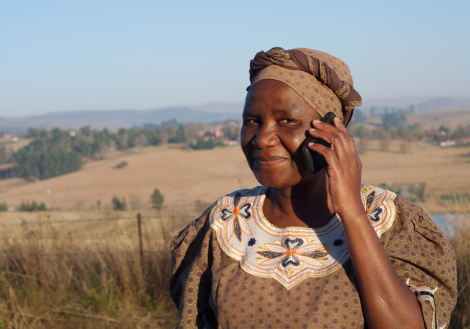 Traditional African Zulu woman speaking on mobile cell phone telephone in rural KwaZulu-Natal.