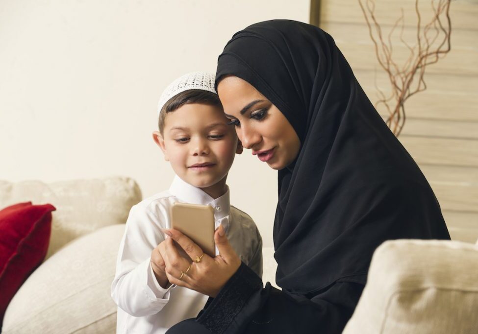 Muslim mother and son using mobile phone.